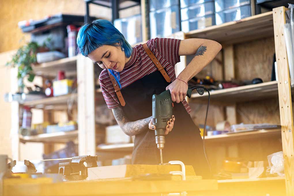 Woman using a drill in an industrial workshop